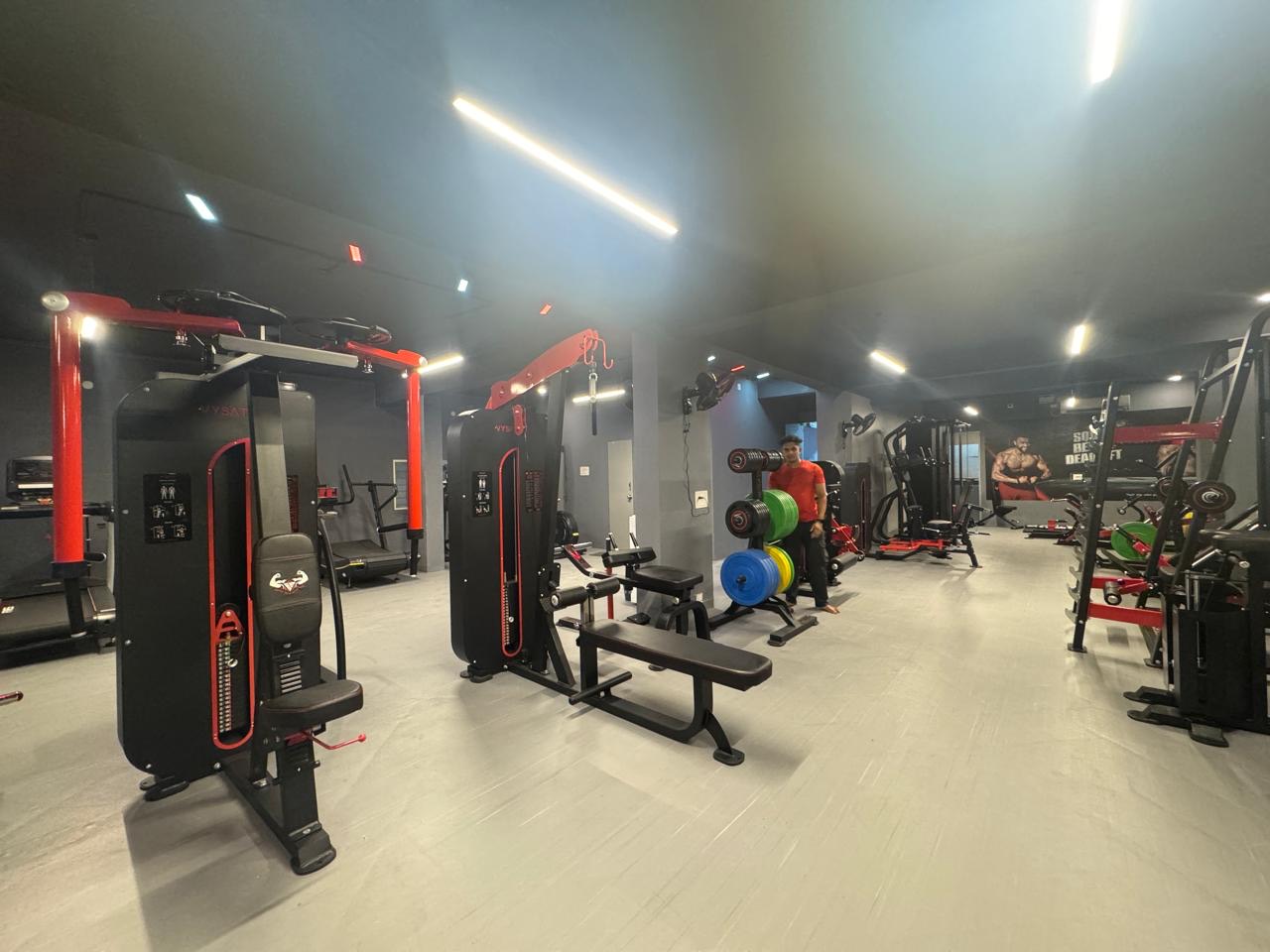 A BurnZone coach in red guiding a member on the machine floor